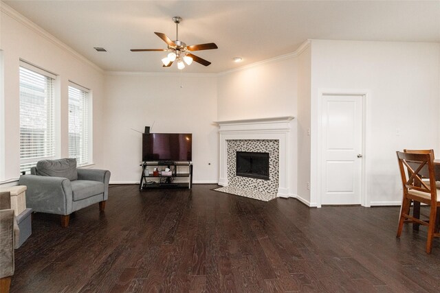 living room with a tiled fireplace, crown molding, and dark hardwood / wood-style flooring