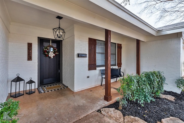 doorway to property with covered porch and brick siding