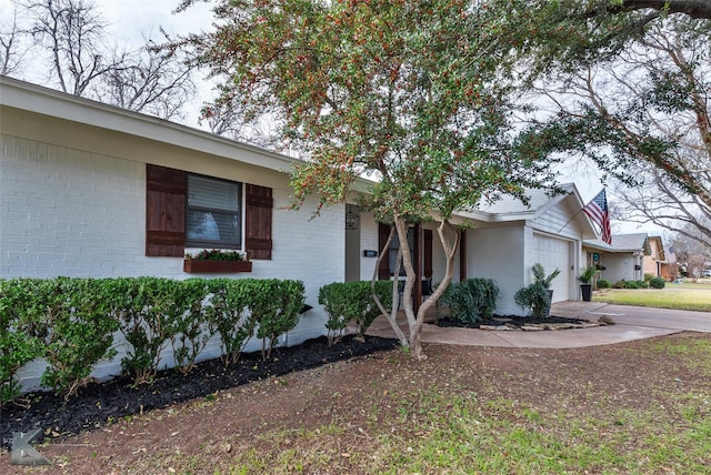 single story home with a garage, driveway, and brick siding