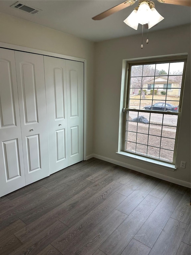 unfurnished bedroom with dark hardwood / wood-style floors, ceiling fan, and a closet