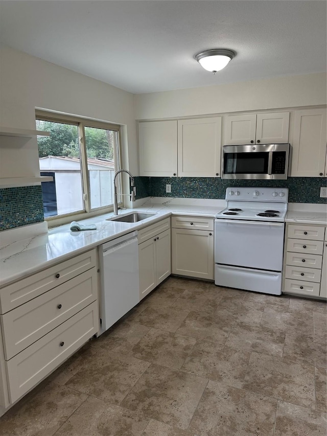 kitchen featuring tasteful backsplash, white cabinetry, sink, light stone countertops, and white appliances