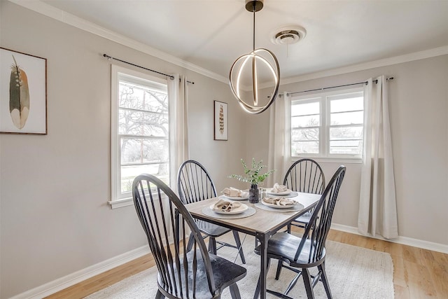 dining area with ornamental molding, a wealth of natural light, and light hardwood / wood-style floors