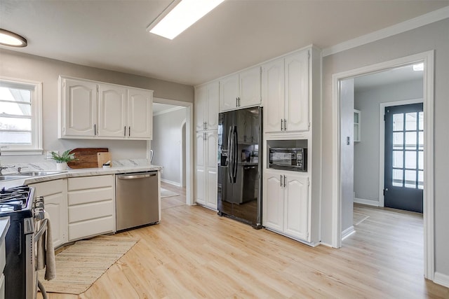 kitchen featuring a wealth of natural light, sink, white cabinets, light hardwood / wood-style floors, and black appliances