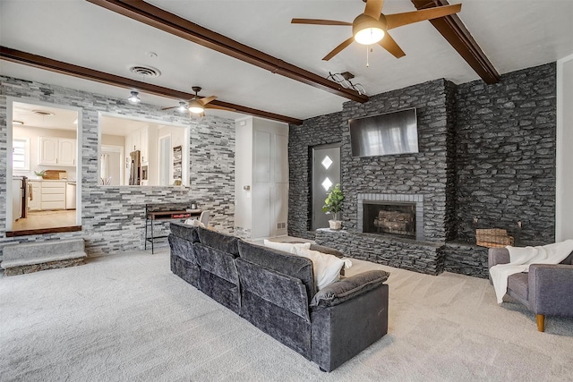 carpeted living room featuring ceiling fan, a fireplace, and beam ceiling