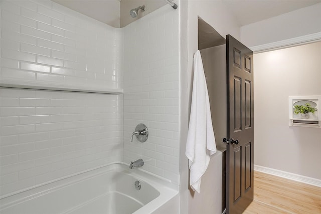 bathroom featuring wood-type flooring and tiled shower / bath