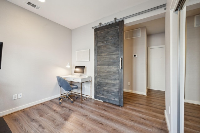 unfurnished office featuring a barn door and light wood-type flooring