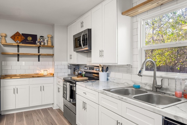 kitchen with white cabinetry, sink, light stone countertops, and appliances with stainless steel finishes