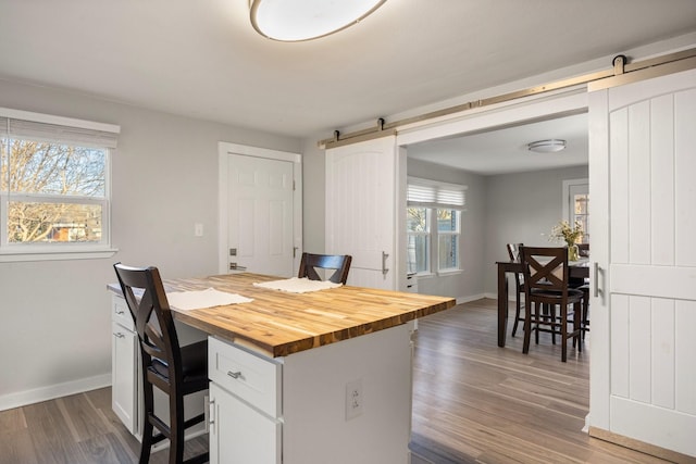 kitchen featuring wood counters, dark hardwood / wood-style flooring, a barn door, and white cabinets