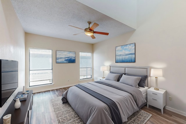 bedroom featuring a textured ceiling, a ceiling fan, baseboards, and wood finished floors