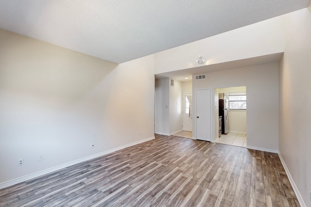 empty room with light hardwood / wood-style flooring and a textured ceiling