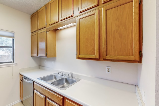 kitchen featuring stainless steel dishwasher, light countertops, a textured ceiling, and a sink