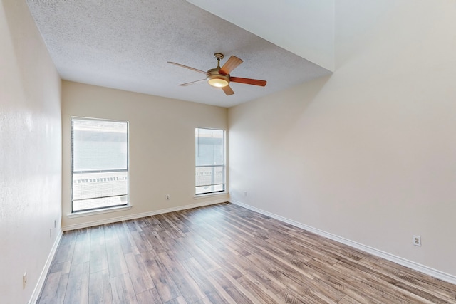 unfurnished room featuring ceiling fan, baseboards, a textured ceiling, and wood finished floors