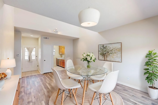 dining room with light wood-type flooring, visible vents, and baseboards