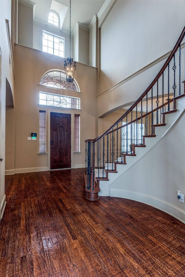 entryway with ornamental molding, a chandelier, hardwood / wood-style floors, and a high ceiling