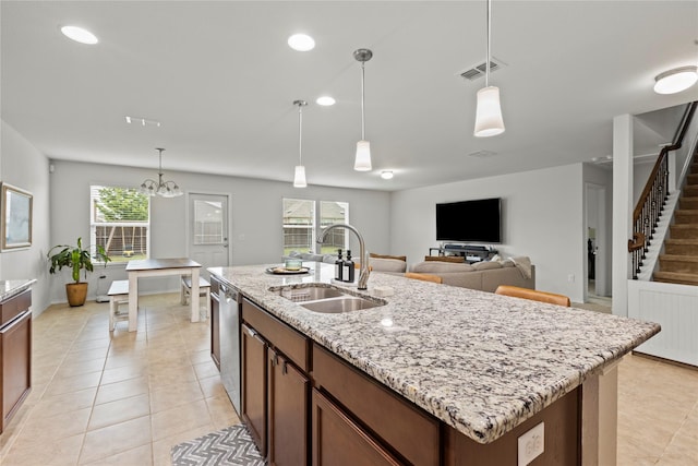 kitchen with sink, hanging light fixtures, light stone counters, a center island with sink, and stainless steel dishwasher