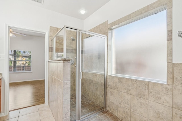 bathroom featuring tile patterned flooring, a shower with shower door, and ceiling fan