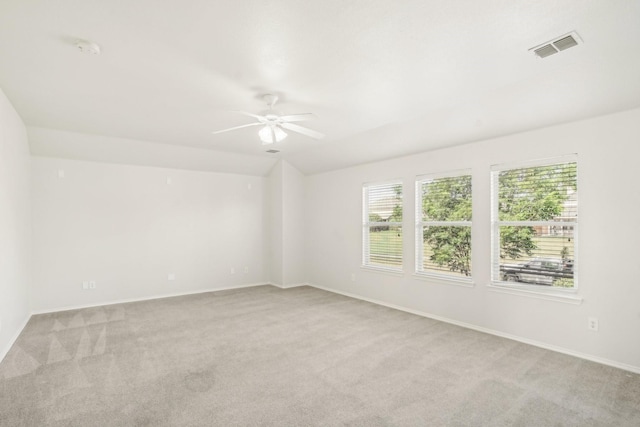 spare room featuring ceiling fan, lofted ceiling, and light carpet