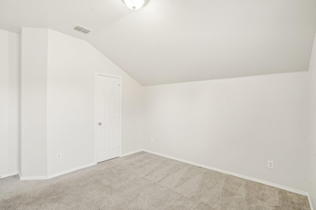 additional living space with light colored carpet and vaulted ceiling