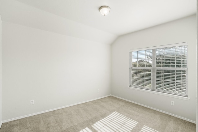 unfurnished room featuring lofted ceiling and light colored carpet