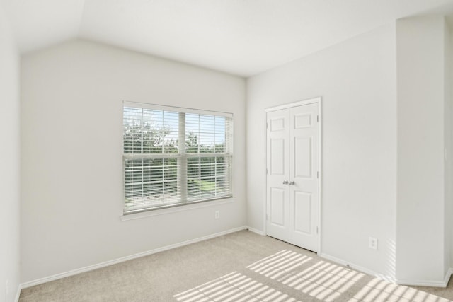 unfurnished bedroom featuring lofted ceiling, light colored carpet, and a closet