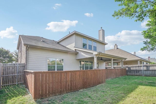 rear view of house with ceiling fan and a lawn