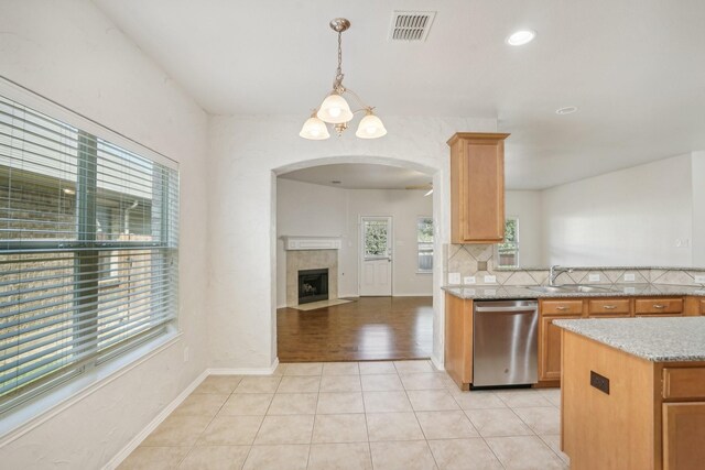 kitchen featuring light tile patterned flooring, sink, tasteful backsplash, decorative light fixtures, and dishwasher