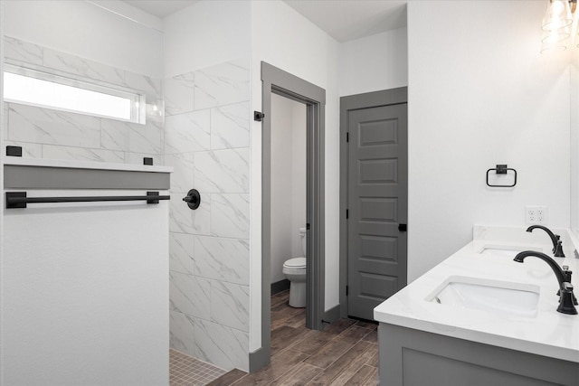 bathroom with vanity, toilet, and tiled shower