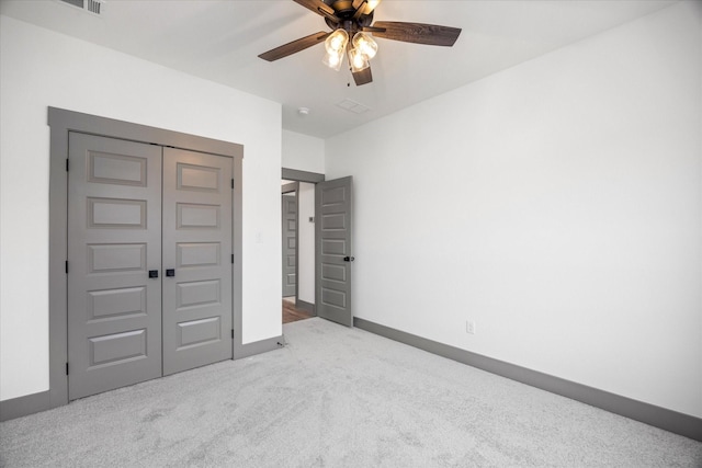 unfurnished bedroom featuring light colored carpet, ceiling fan, and a closet