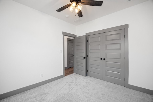 unfurnished bedroom with light colored carpet, ceiling fan, and a closet