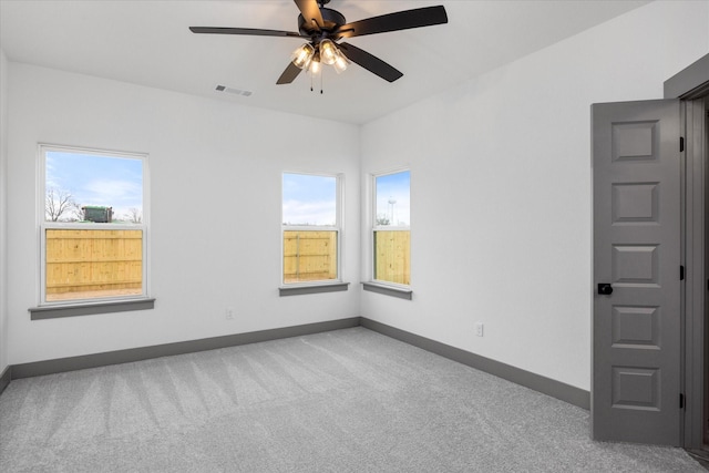 carpeted spare room with ceiling fan and a healthy amount of sunlight