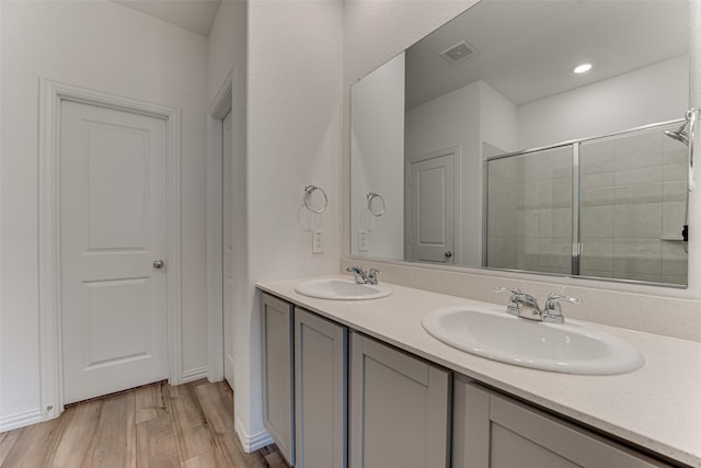 bathroom with hardwood / wood-style floors, vanity, and a shower with door