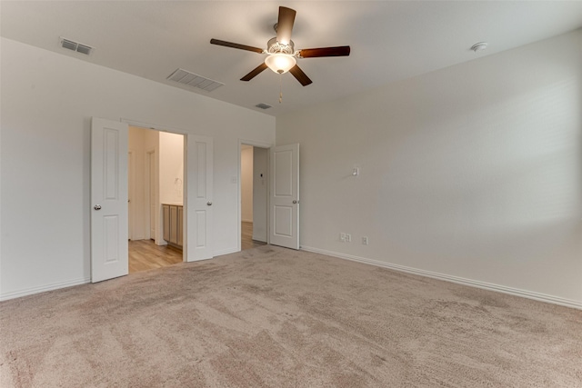 unfurnished bedroom with ensuite bathroom, ceiling fan, and light colored carpet