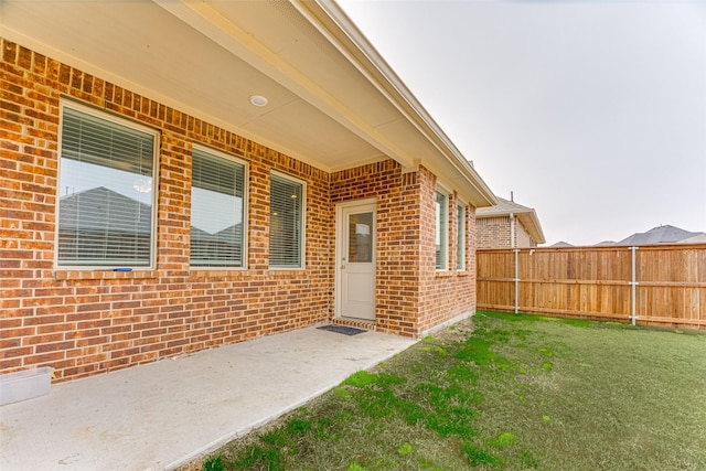 property entrance featuring a lawn and a patio area