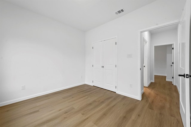 unfurnished bedroom with light hardwood / wood-style floors and a closet