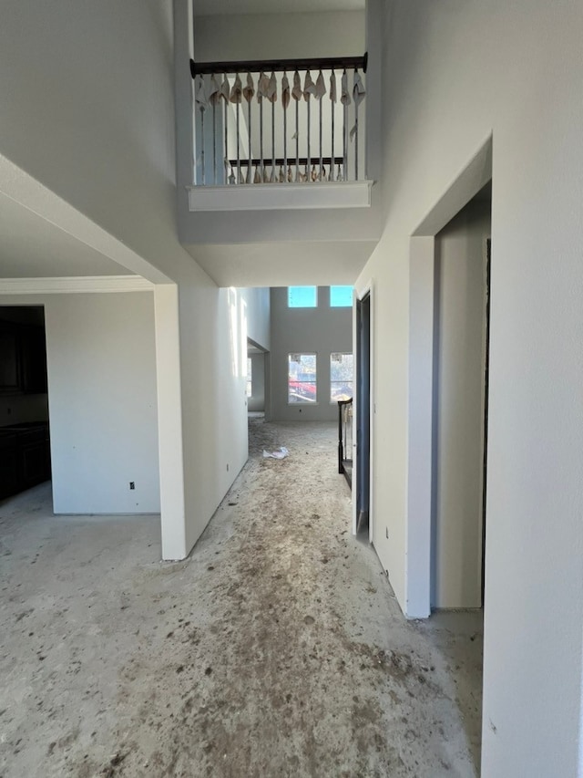 corridor featuring crown molding and a towering ceiling