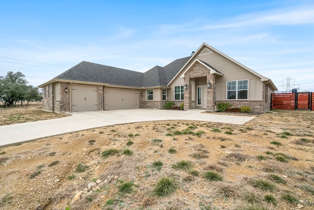 view of front of property featuring an attached garage, driveway, fence, and brick siding