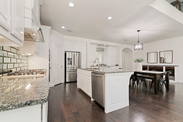 kitchen with pendant lighting, white cabinets, a kitchen island with sink, stainless steel appliances, and light stone countertops