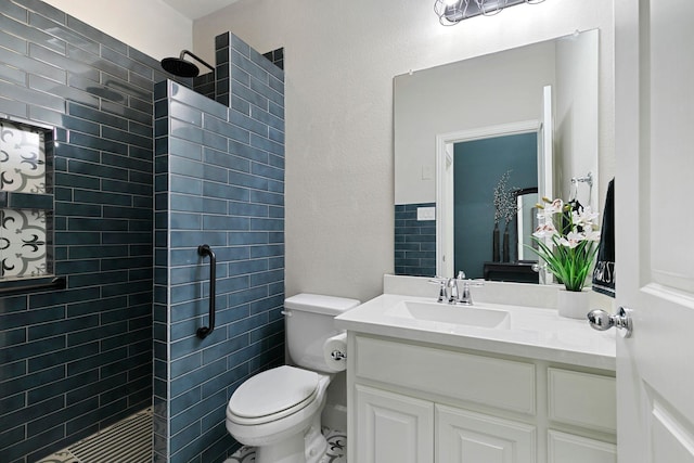 bathroom featuring vanity, a tile shower, and toilet