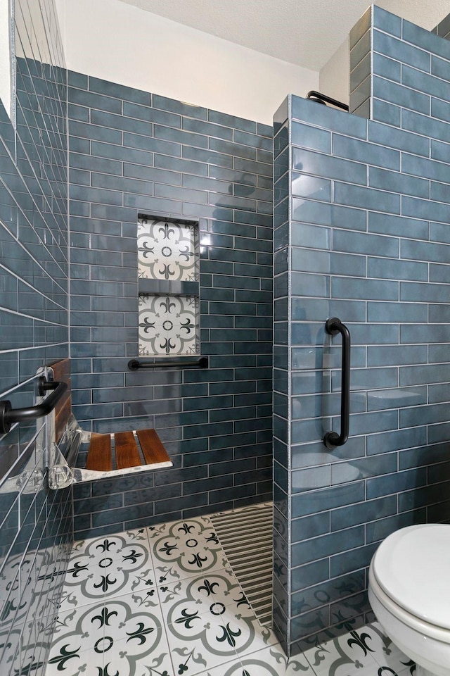 bathroom featuring tile patterned flooring, tiled shower, tile walls, and toilet