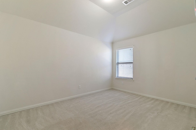 carpeted empty room featuring vaulted ceiling