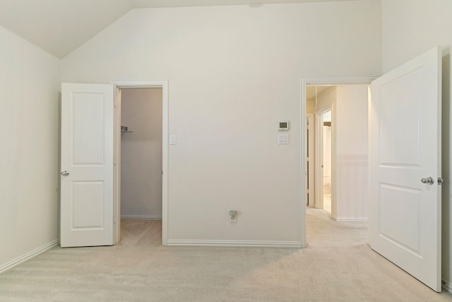 unfurnished bedroom featuring vaulted ceiling, a walk in closet, light carpet, and a closet