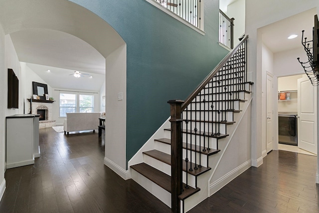 staircase with hardwood / wood-style flooring, ceiling fan, lofted ceiling, and a fireplace