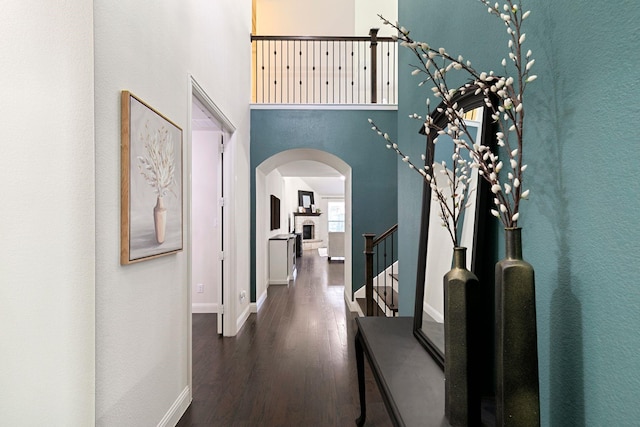 hallway featuring a towering ceiling and dark hardwood / wood-style flooring