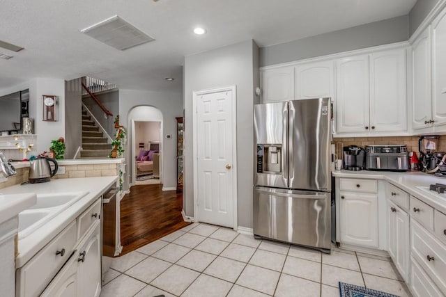 kitchen featuring stainless steel appliances, light tile patterned floors, decorative backsplash, and white cabinets