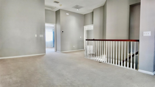 hallway with a towering ceiling and light colored carpet