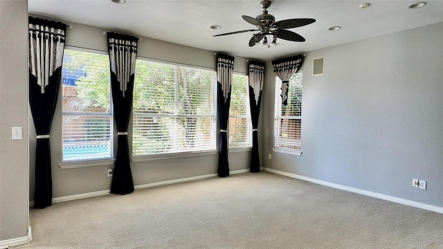 carpeted spare room with ceiling fan and plenty of natural light