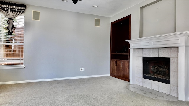 unfurnished living room with light colored carpet and a tiled fireplace