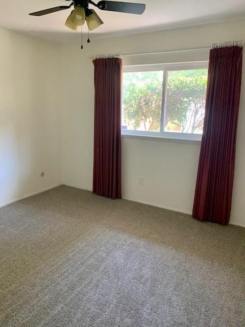 spare room with a wealth of natural light, ceiling fan, and carpet flooring