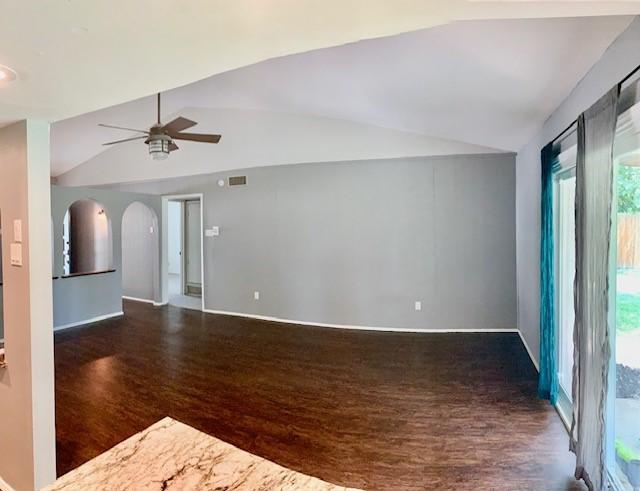 empty room featuring vaulted ceiling, dark hardwood / wood-style floors, and ceiling fan