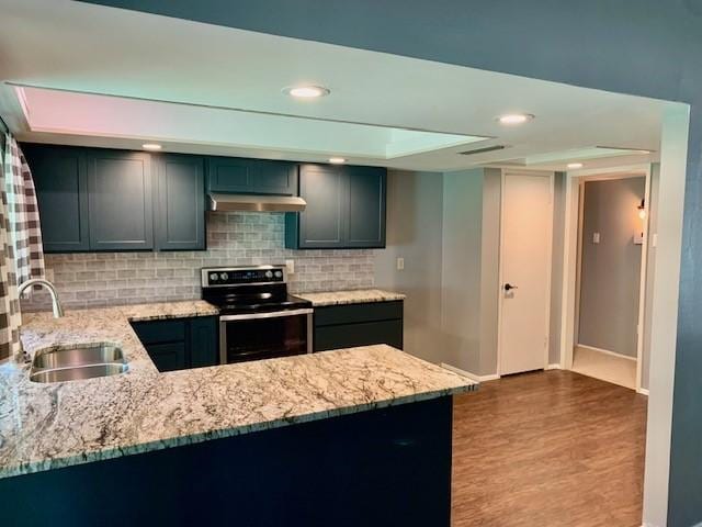 kitchen featuring sink, stainless steel electric range, light stone counters, decorative backsplash, and kitchen peninsula